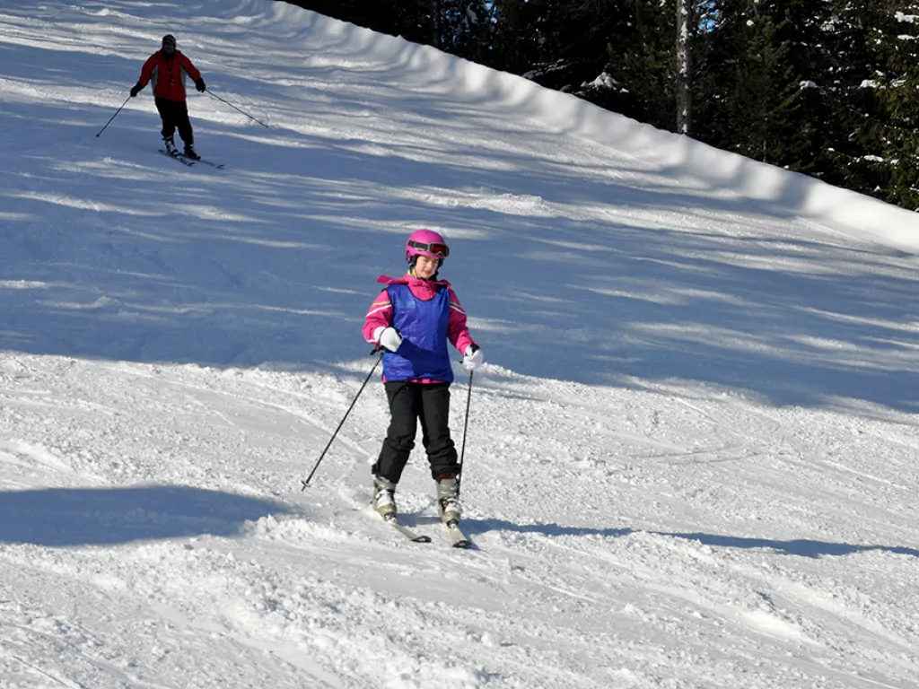 Skifahrerin in pinker Jacke auf der Piste.